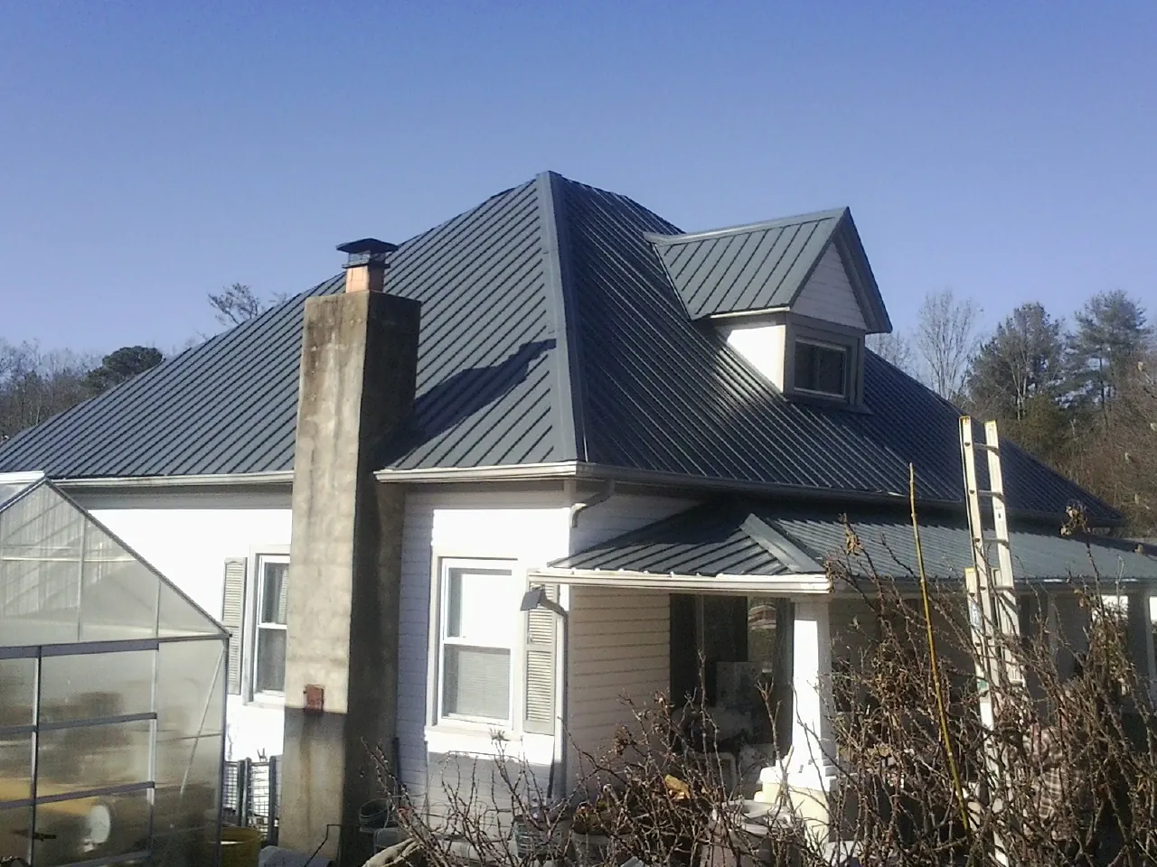 Dark blue standing seam metal roof on a white farmhouse with dormer — Slate & Tile Roof Repair by Roofing Brothers in Mellott