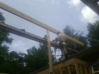 Carpenter setting a ridge beam over a new addition frame — Ice Dam Removal by Roofing Brothers in Mellott