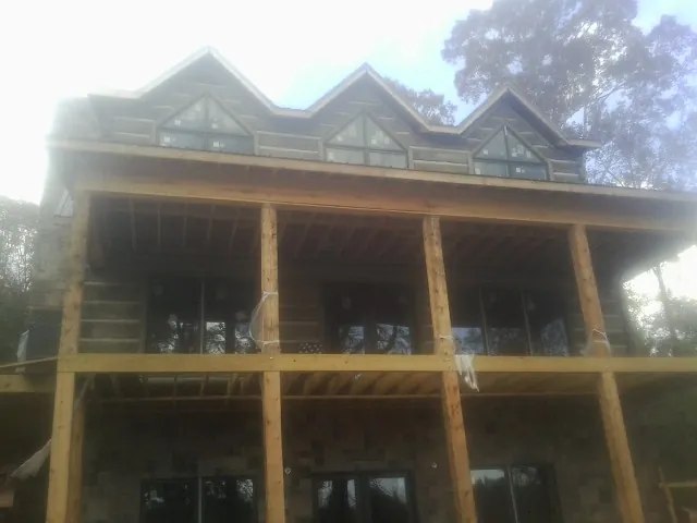 Dormers and porch framing on a large log home under construction — Roof Coating work by our crew in Mellott