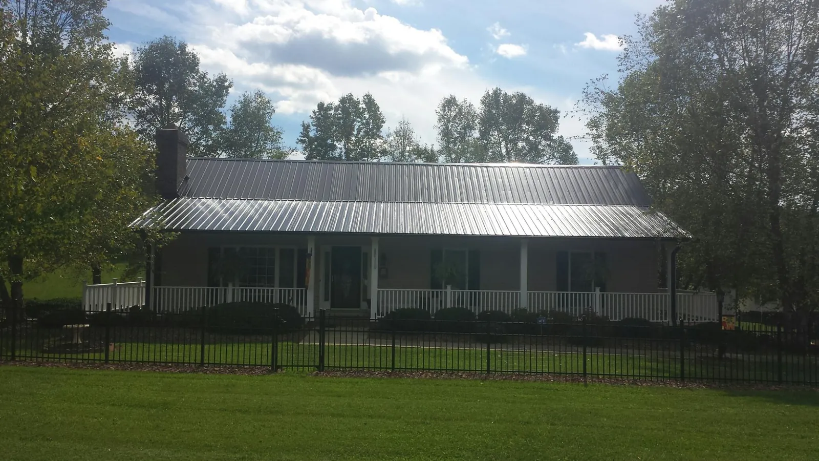 Gray metal roof on a brick ranch with a full width front porch — Gutter Guard Installation work by our crew in Mellott