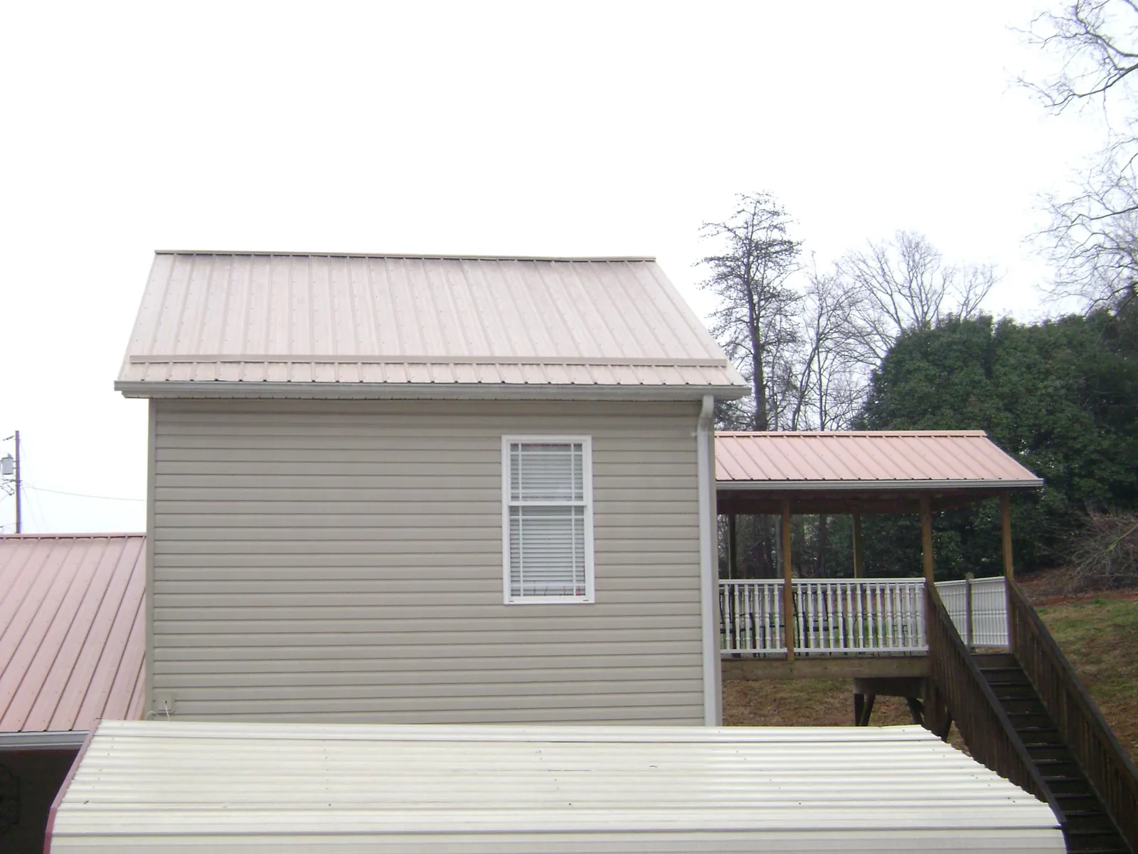 Tan metal roofs on a two story addition and attached porch, from a Roof Replacement job in Mellott