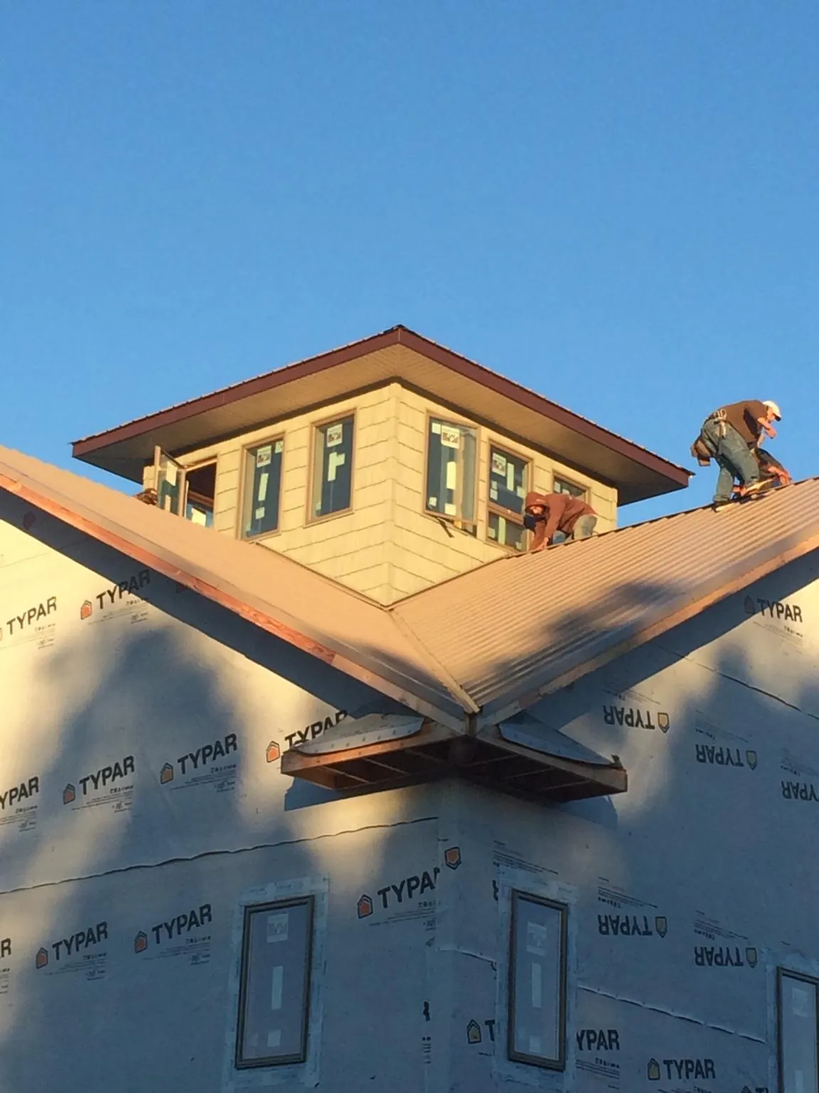 Roofers working around a rooftop cupola on a new metal roof at sunset — Roof Waterproofing in Mellott by Roofing Brothers